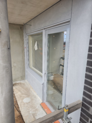 Kerrostaloparvekkeen oven ja ikkunan vaaleanharmaat peltilistoitukset.