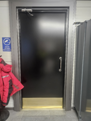 Oman hallin mustaksi pellitetty valkoinen ovi sekä hopeiset pielipellit.