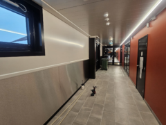 Raahen liikuntahalli: seinään asennetut RST-pellit, yläosan 1 mm valkoiset pellit sekä ikkunoiden ja ovien mustat pielipellit.